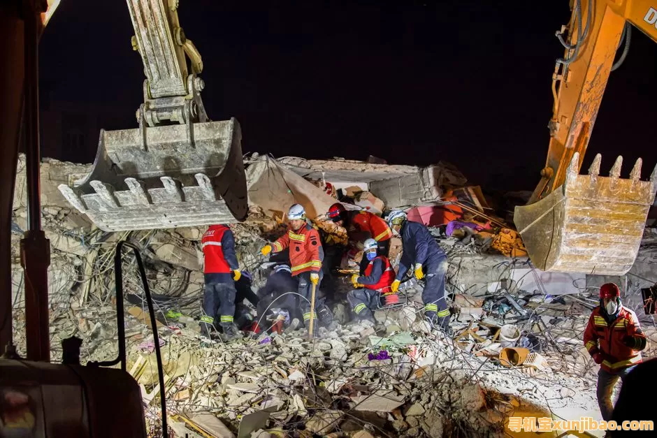 Emergency workers conduct a nighttime rescue amidst earthquake debris and heavy machinery.