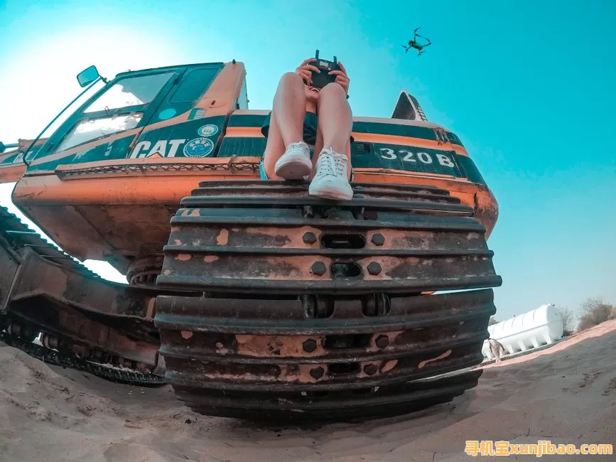 A woman controls a drone from a construction vehicle in Dubai's desert landscape.