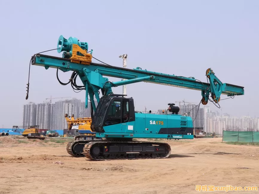 Blue piling rig machine at a construction site in Faridabad, India, with cityscape in background.